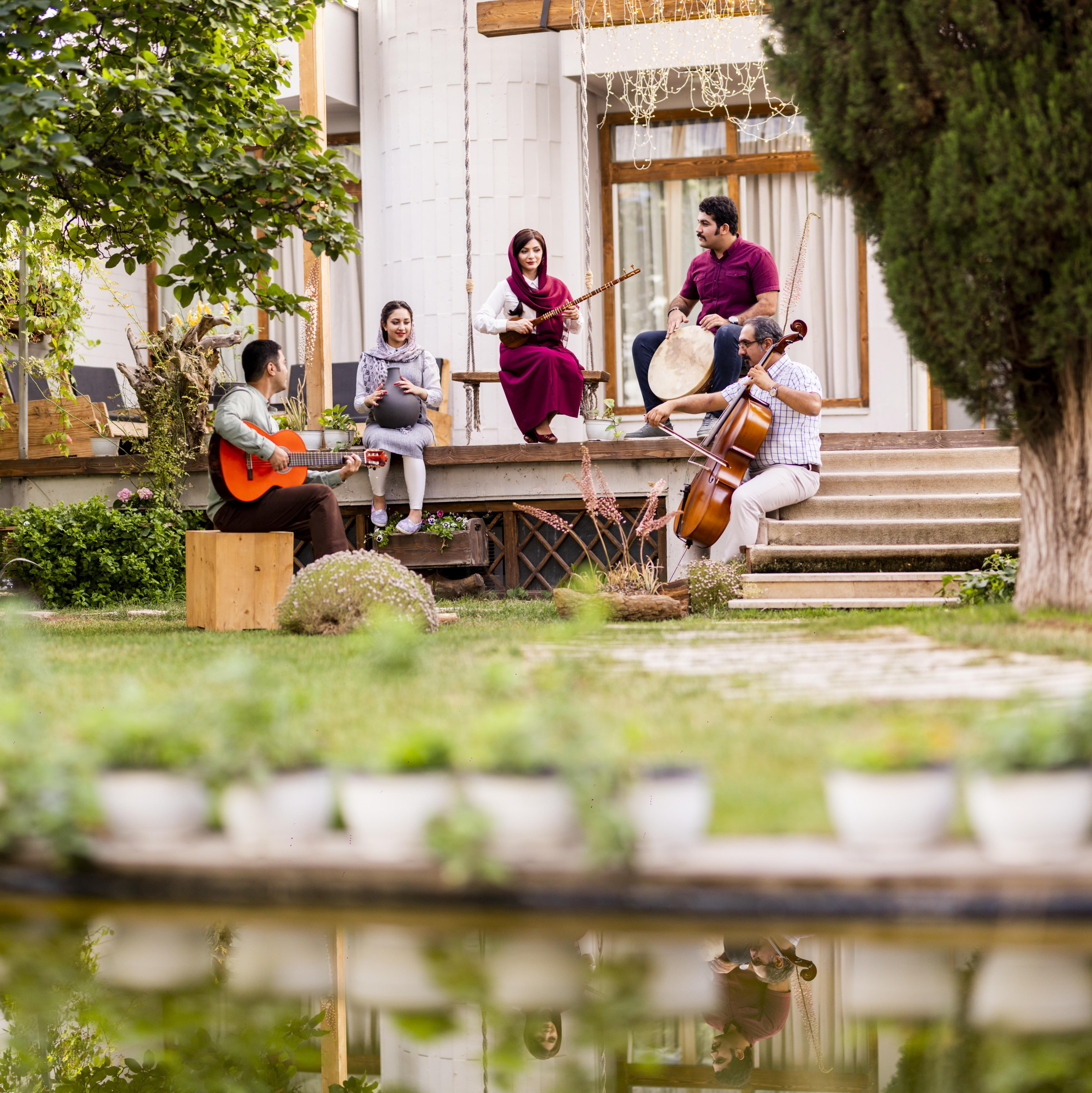 Five musicians with instruments beside a reflecting pool