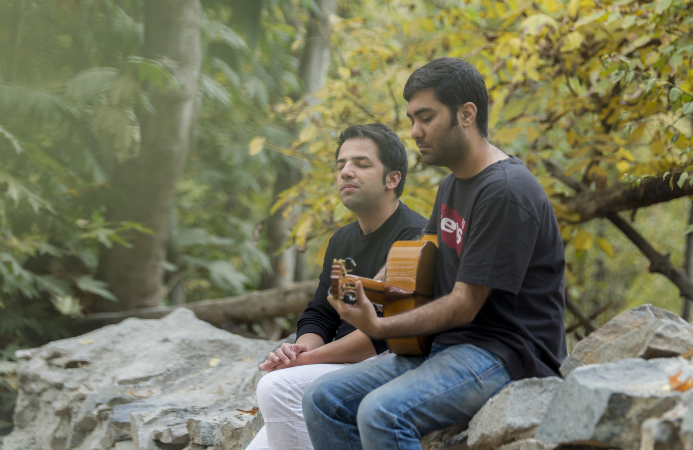 Two people seated outdoors with an acoustic guitar