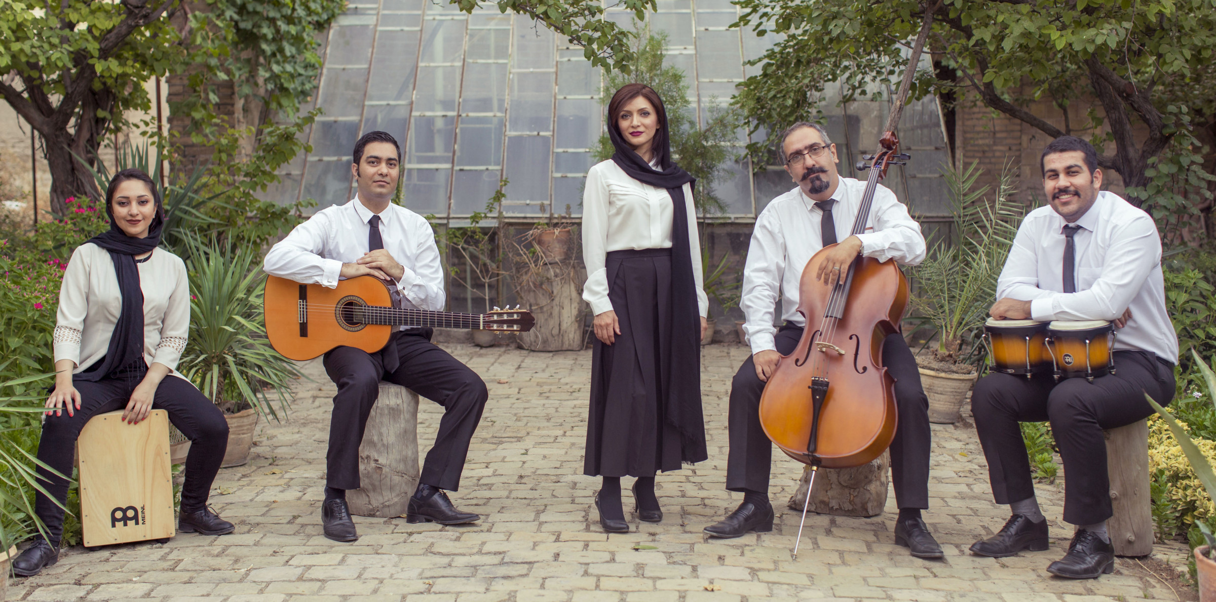 Five musicians with guitar, cello and percussion in a garden