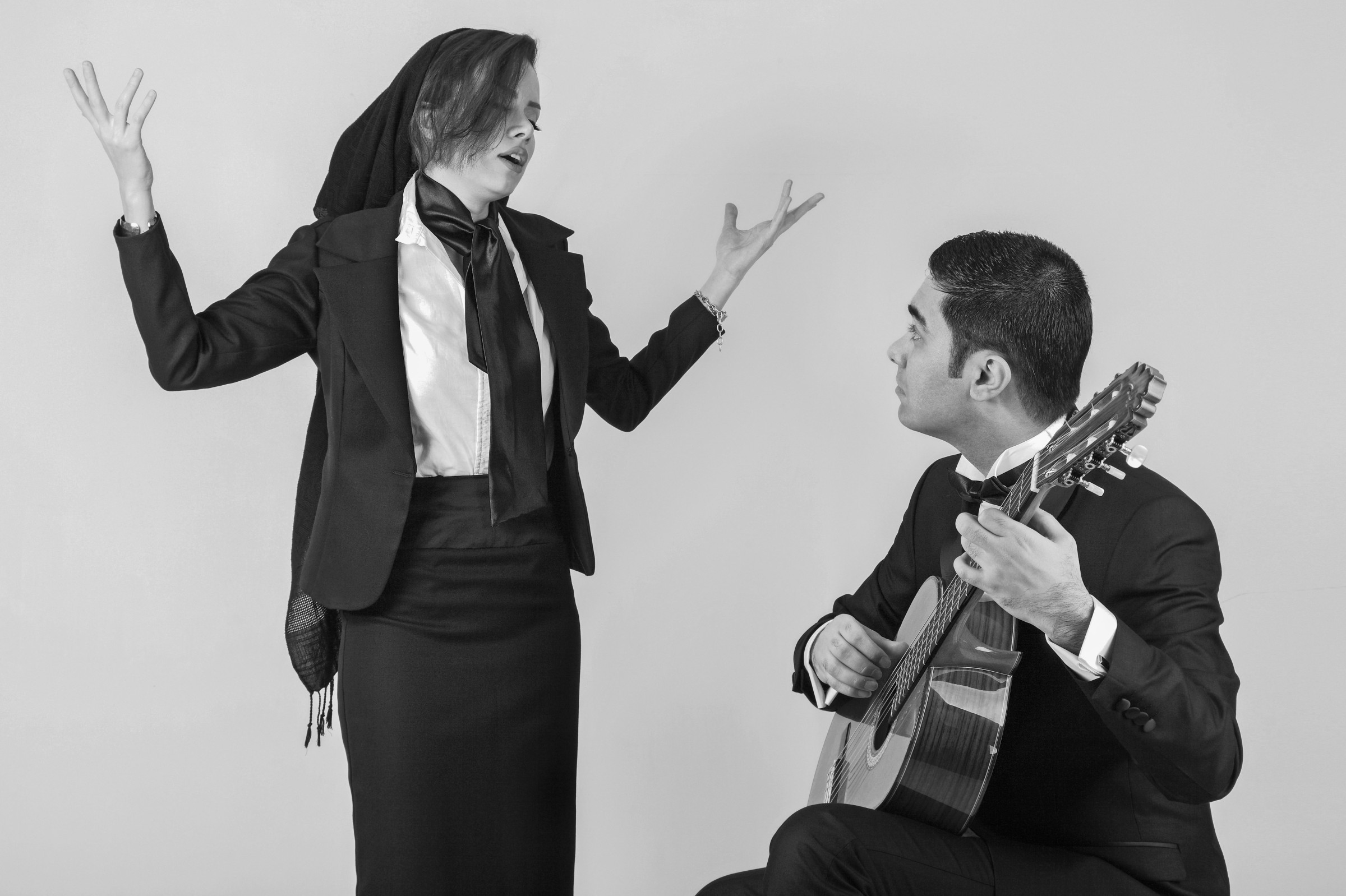 A woman singing beside an acoustic guitarist in a monochrome photograph
