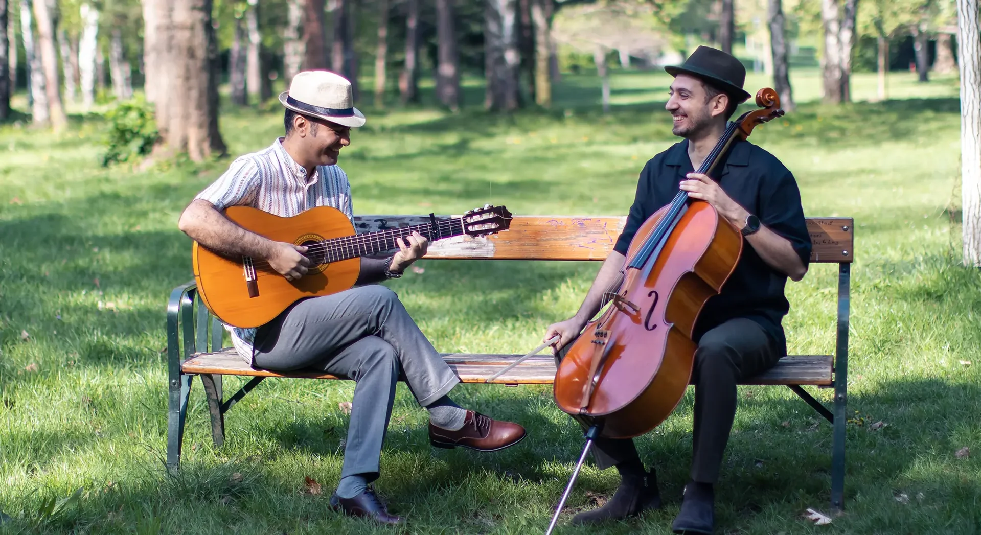 Two Hooniak musicians playing guitar and cello in a woodland