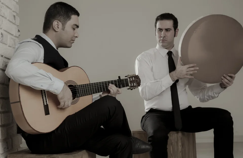 Two musicians playing guitar and frame drum